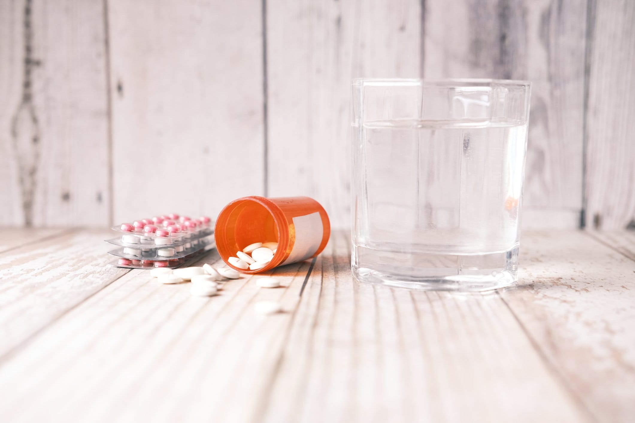 medical pill, blister pack and glass of water on table