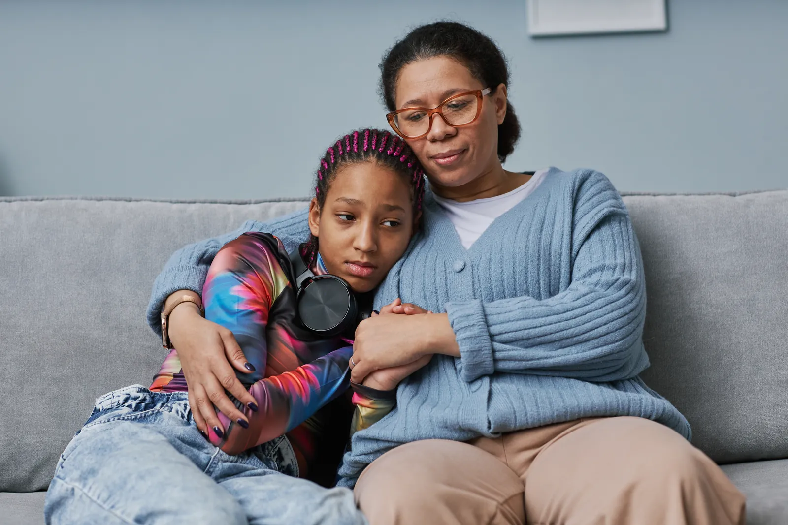 Mother hugging her teenage daughter on the sofa at home