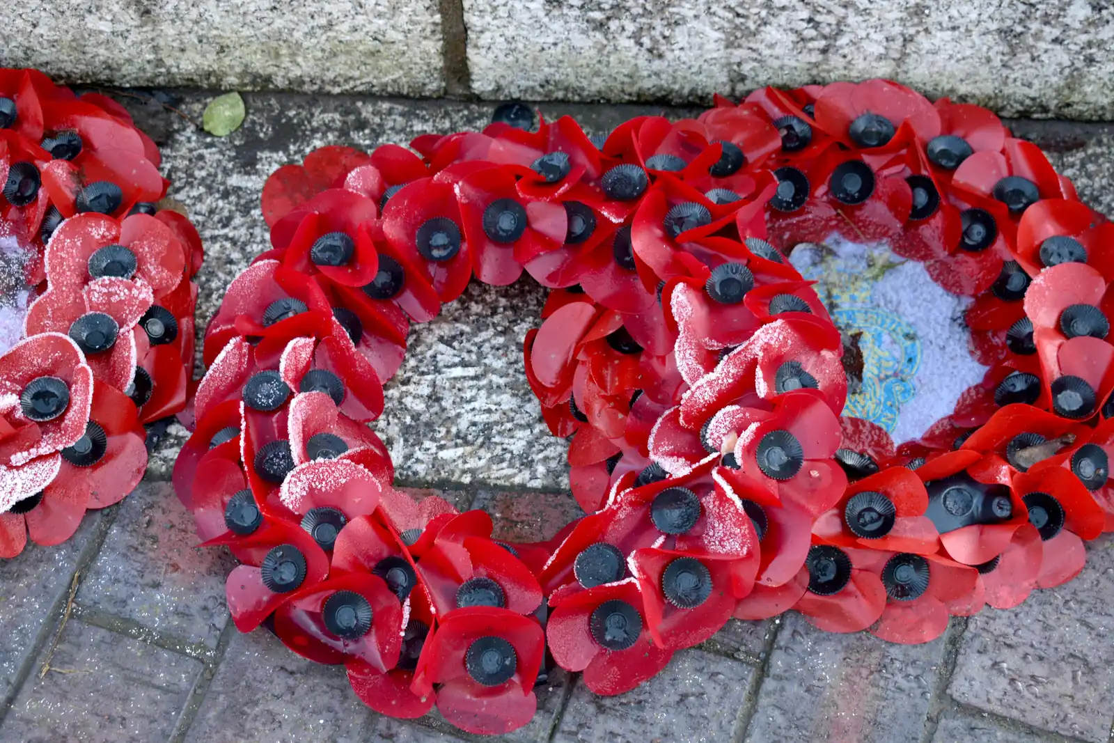Red poppy wreaths laid beneath a war memorial in remembrance