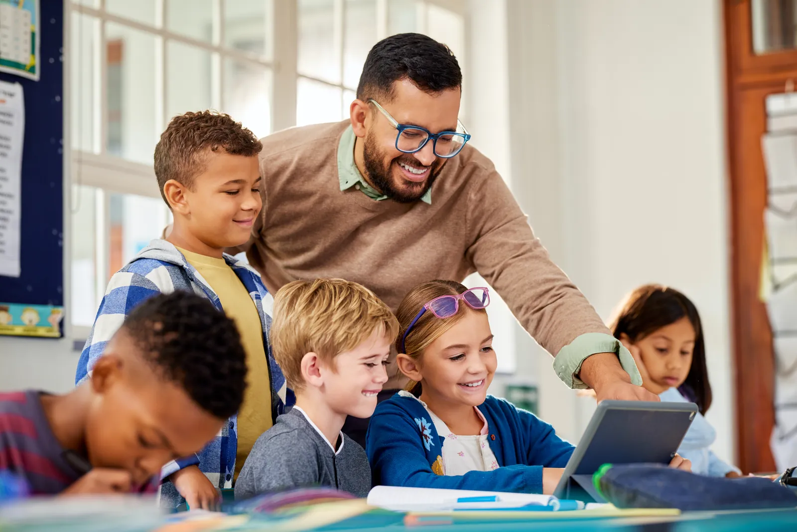 National Teacher Day in the USA: Teacher helping pupils with their work in a classroom