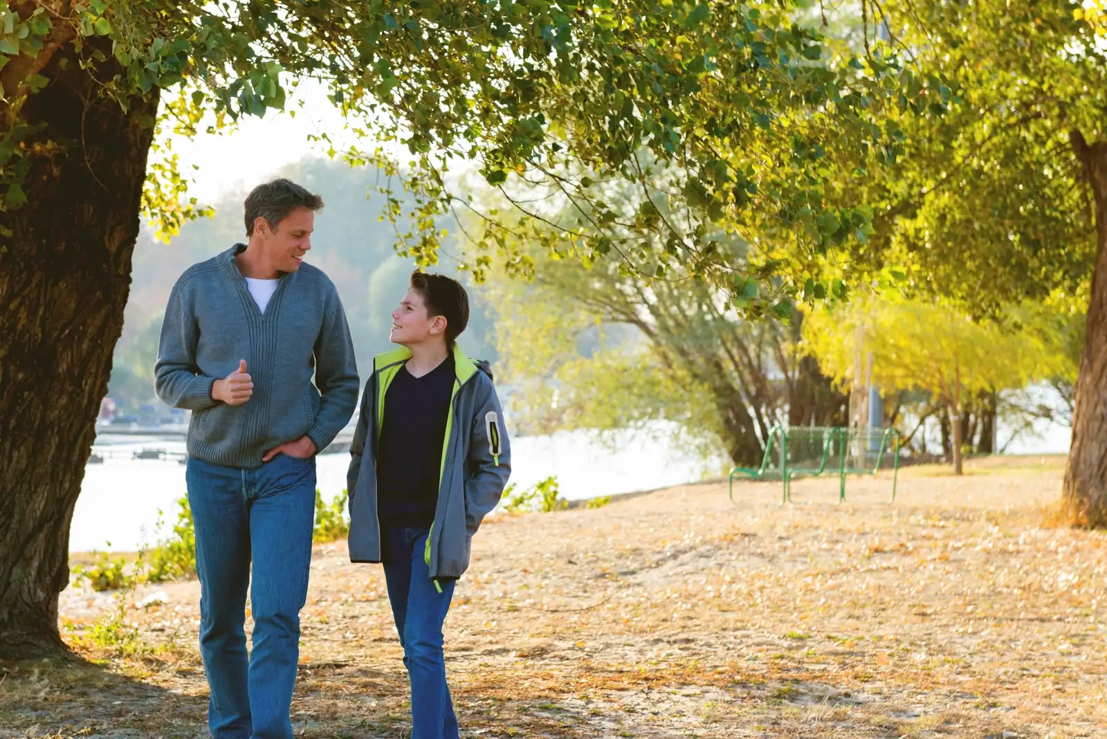 Father and son walking together through a park in autumn
