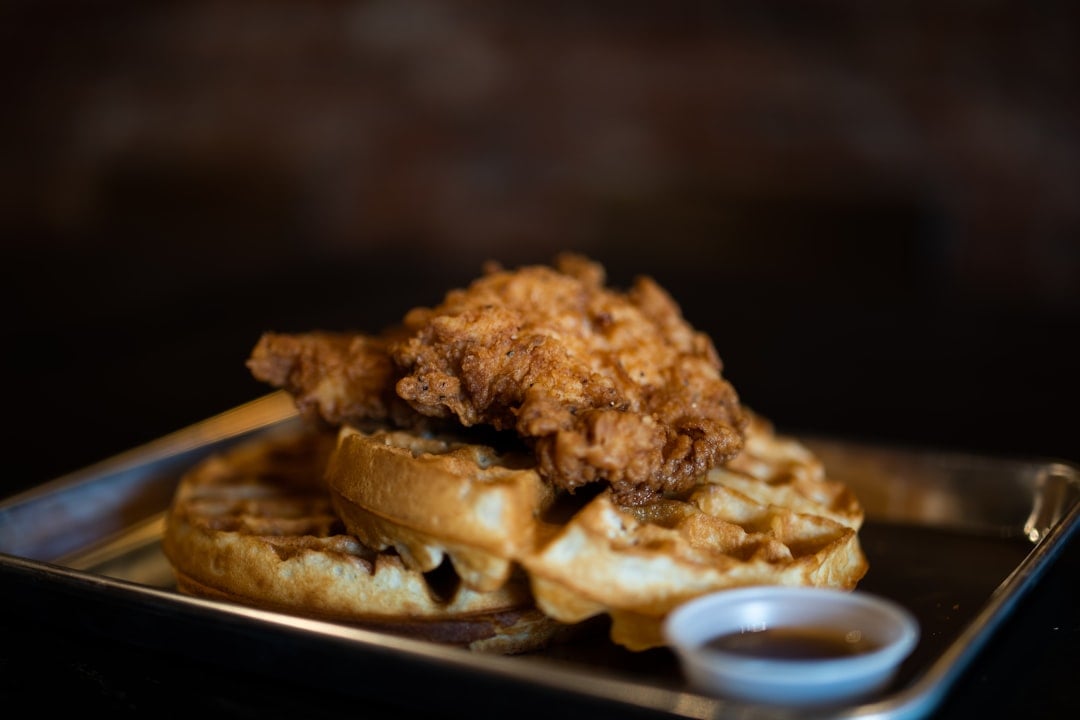 A plate of fried chicken and waffles with maple syrup