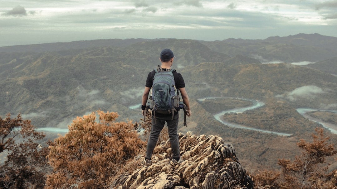 A hiker standing on a mountain summit looking out over the peaks