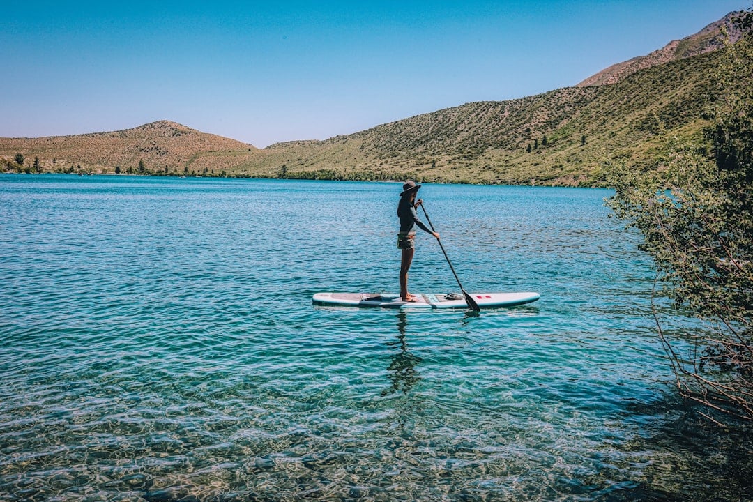 A person stand up paddleboarding on calm water for National SUP Day