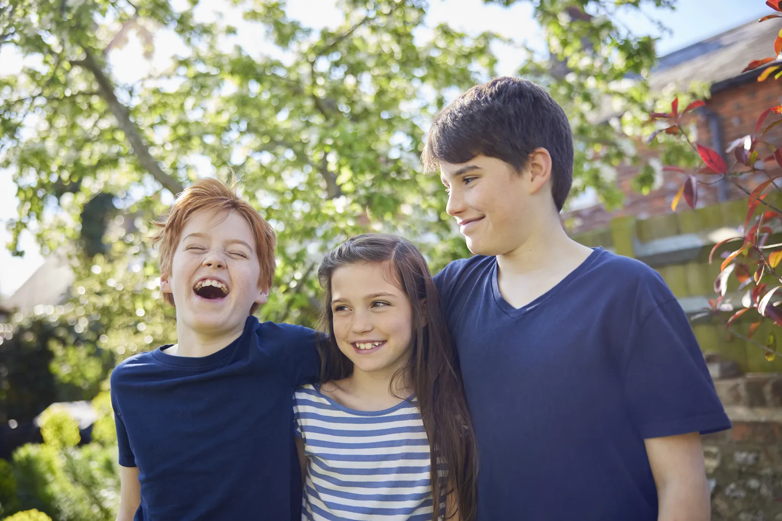 National Middle Child Day: Three siblings laughing together outdoors